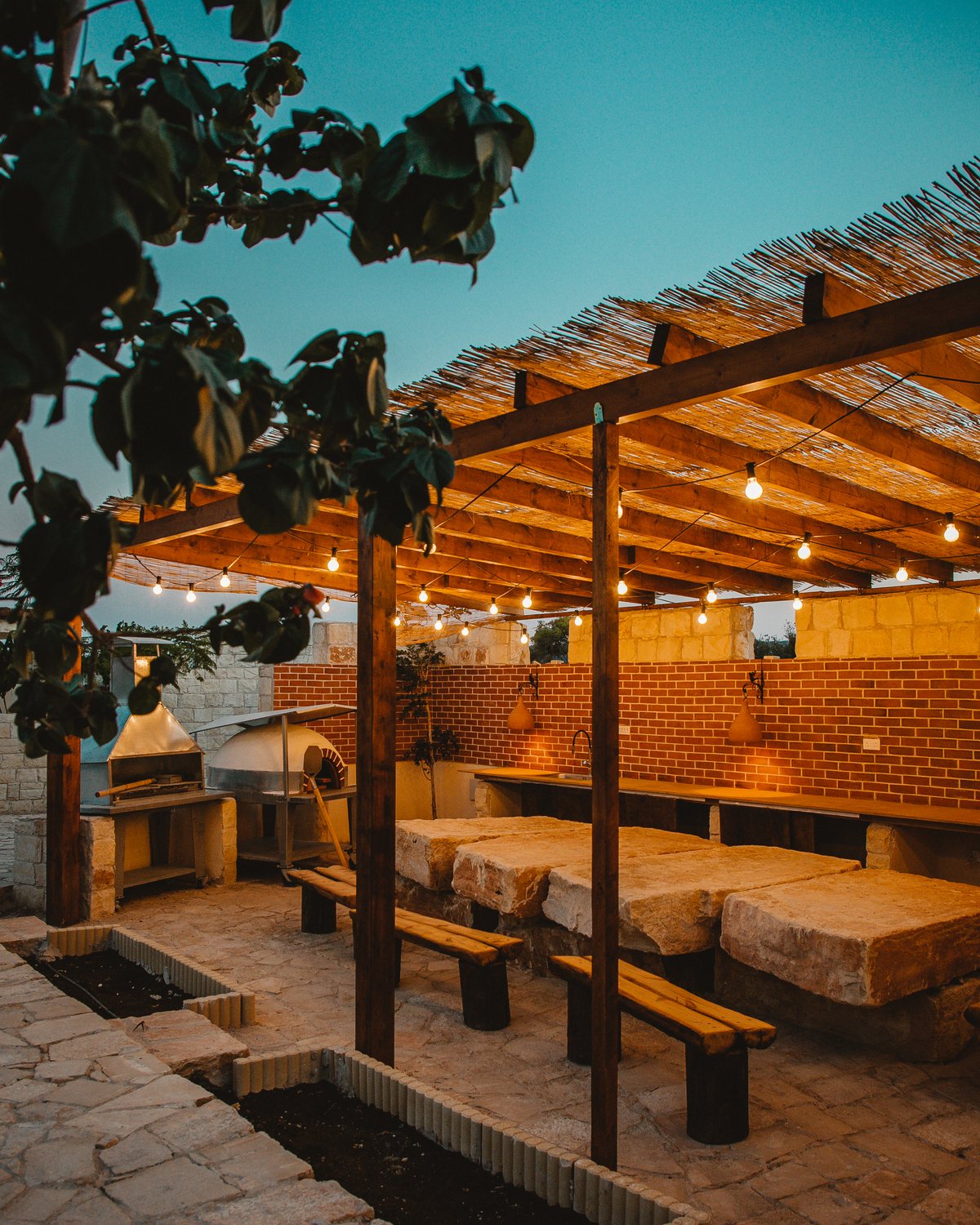 Stone courtyard at Kleos Noble Retreat with olive trees and warm afternoon light
