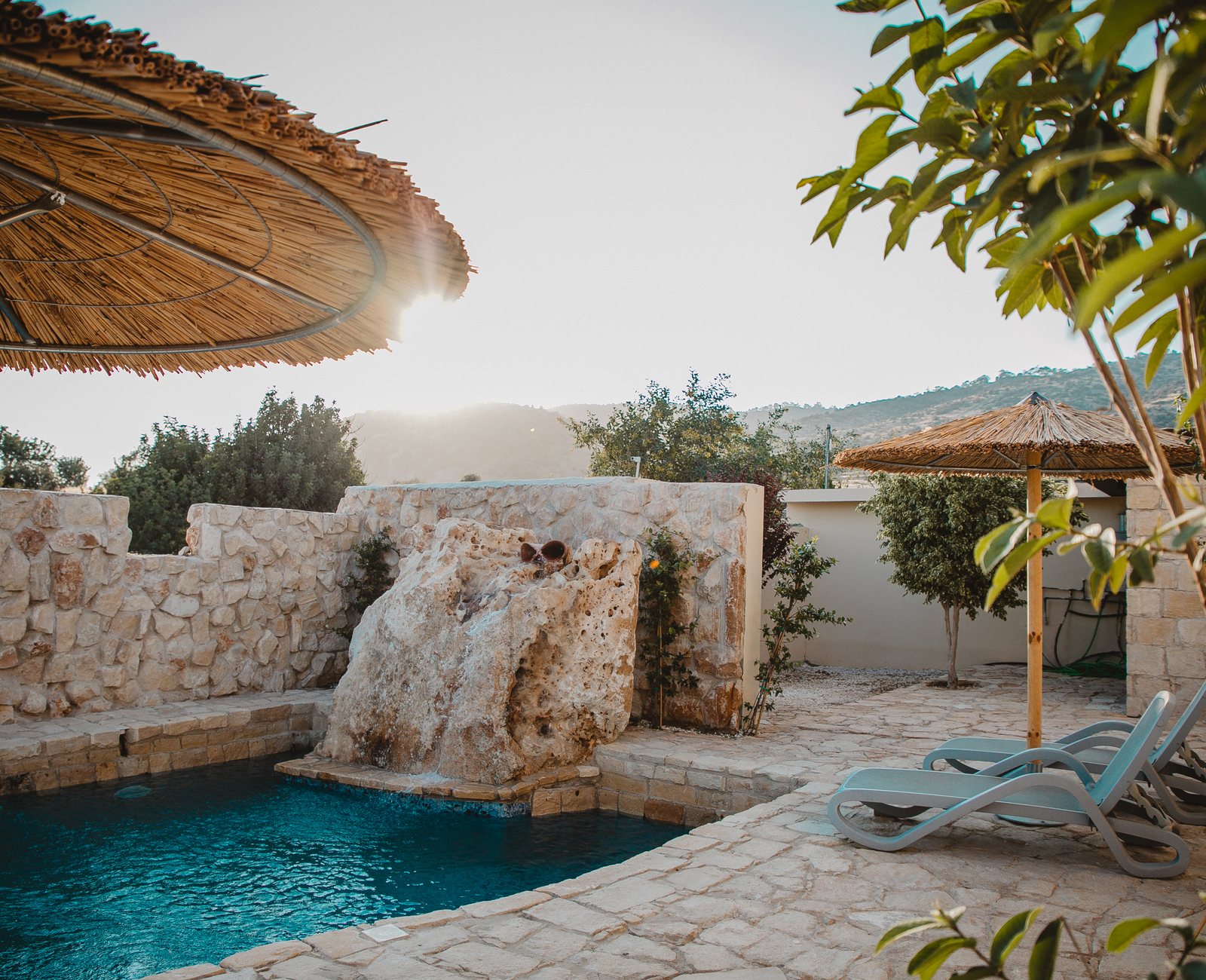 Outdoor pool with olive trees and stone terraces at Kleos